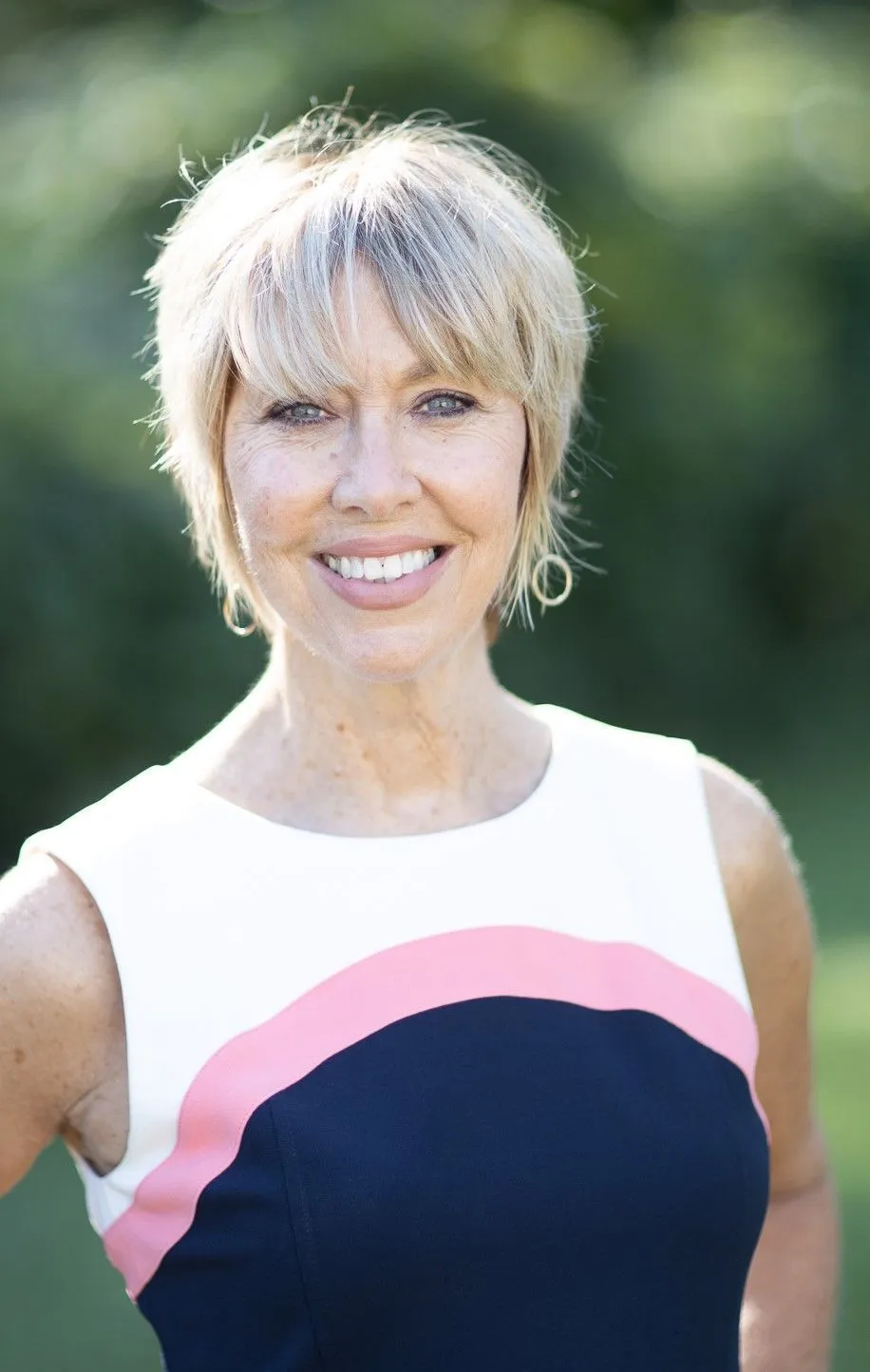 A woman in a pink and blue dress is smiling for the camera.