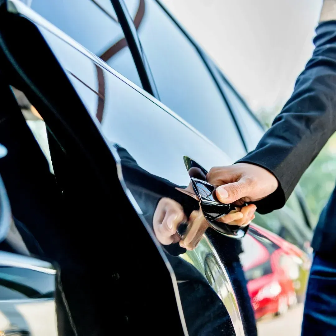 Person unlocking a black car door with a key fob, close-up view