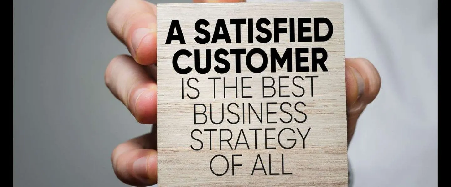 A person is holding a piece of paper that says a satisfied customer is the best business strategy of all.
